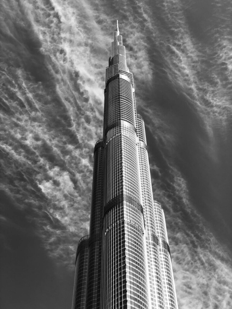Black-and-white image of Burj Khalifa reaching into a dramatic cloudy sky in Dubai.