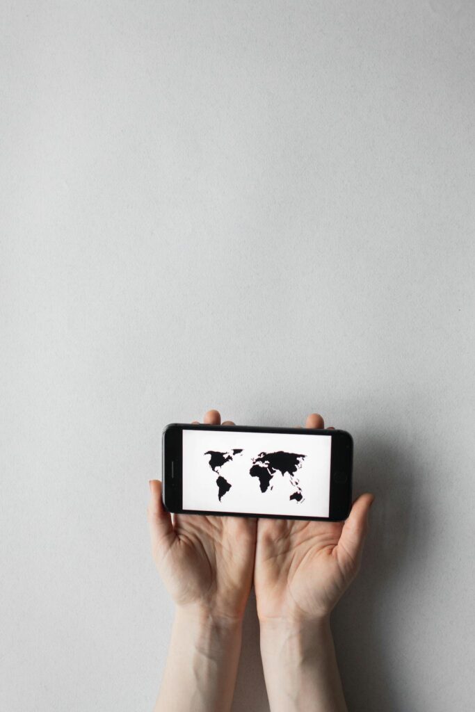 Hands holding a smartphone displaying a world map on a white background, emphasizing global connectivity.